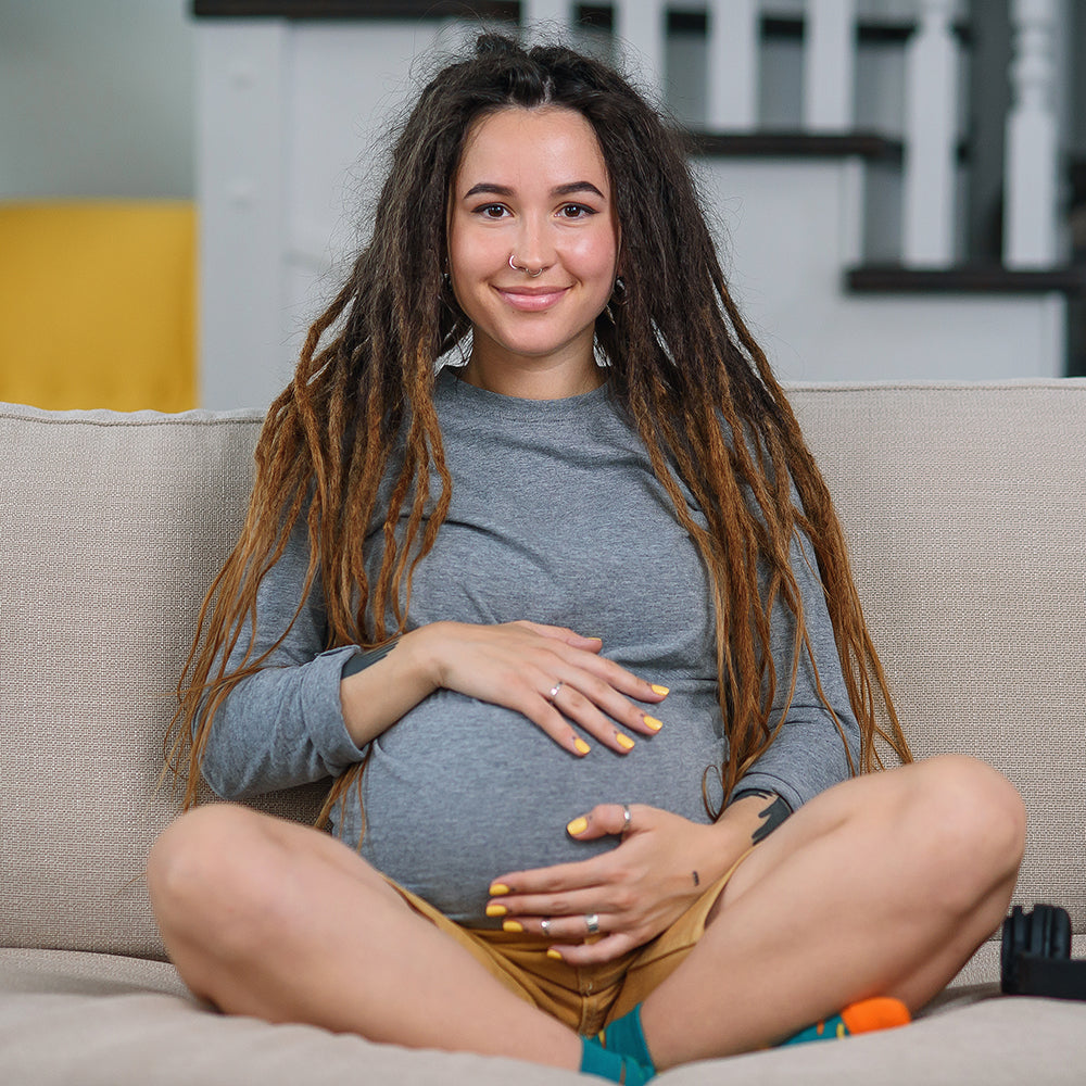 Pregnant woman with dreadlocks and nostril piercing holding belly