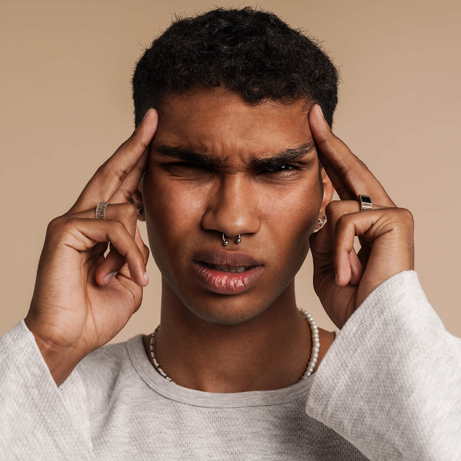 African man with septum piercing confused holding fingers to temples